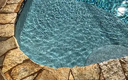 Luxury custom pool with turquoise water and natural stone decking in high-end residential backyard design