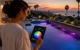 Woman controlling luxury pool lighting via mobile app at sunset resort