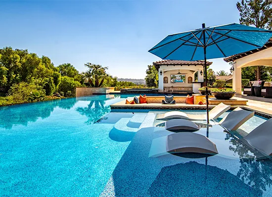 Luxury custom pool construction with integrated spa, loungers, and covered patio area
