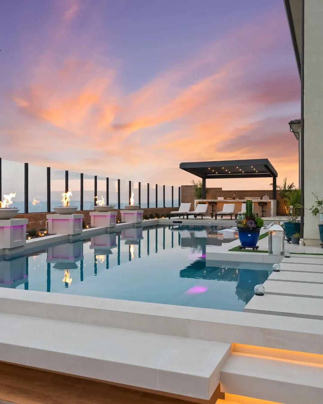 Luxury rooftop pool with custom water features, lounge seating, and sunset ocean views