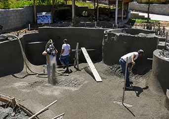 Construction crew executing custom pool build process in excavated residential pool foundation