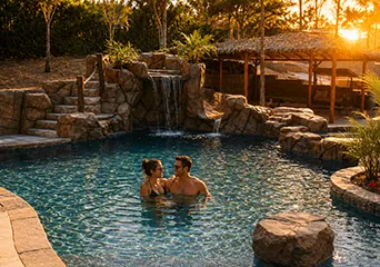 Couple enjoying luxury custom pool at sunset with natural stone features and spa installation