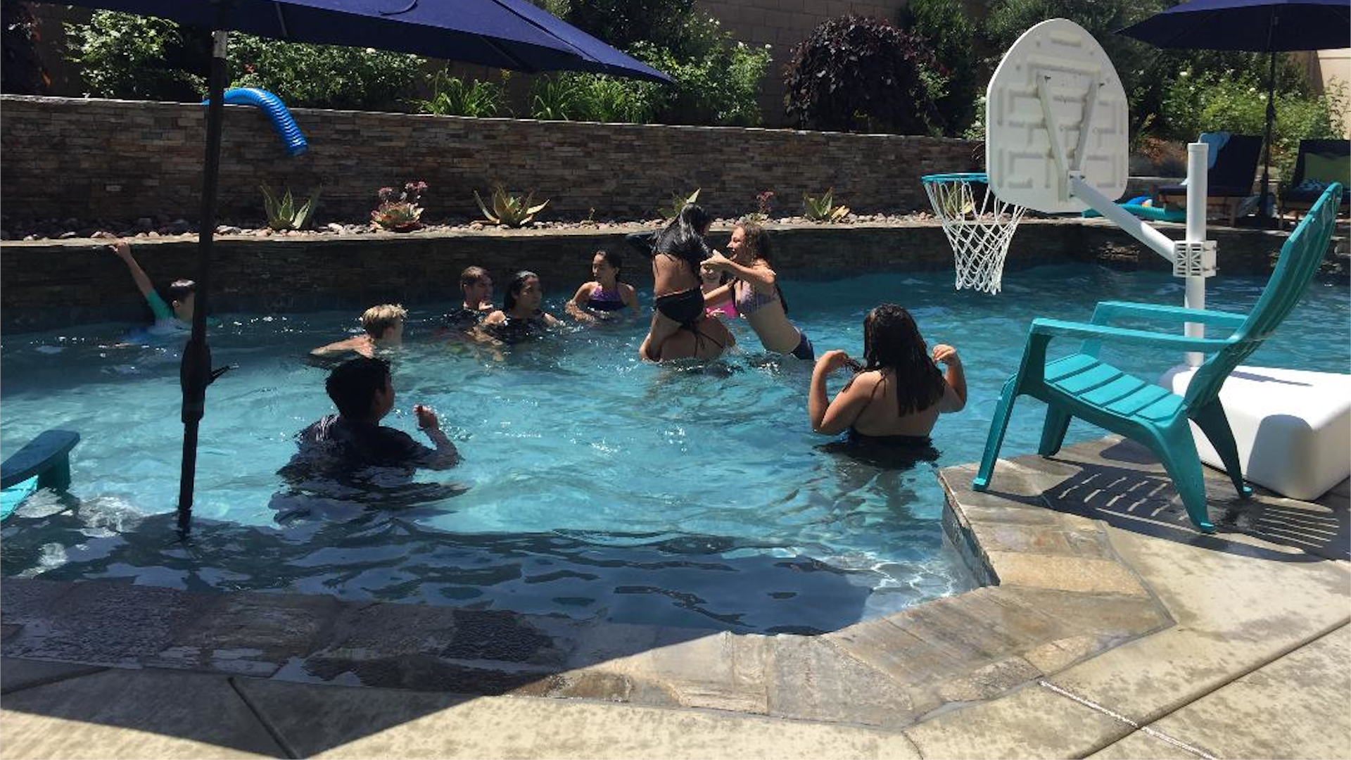 Luxury backyard pool with basketball hoop, spa features, and custom lounge seating for entertaining