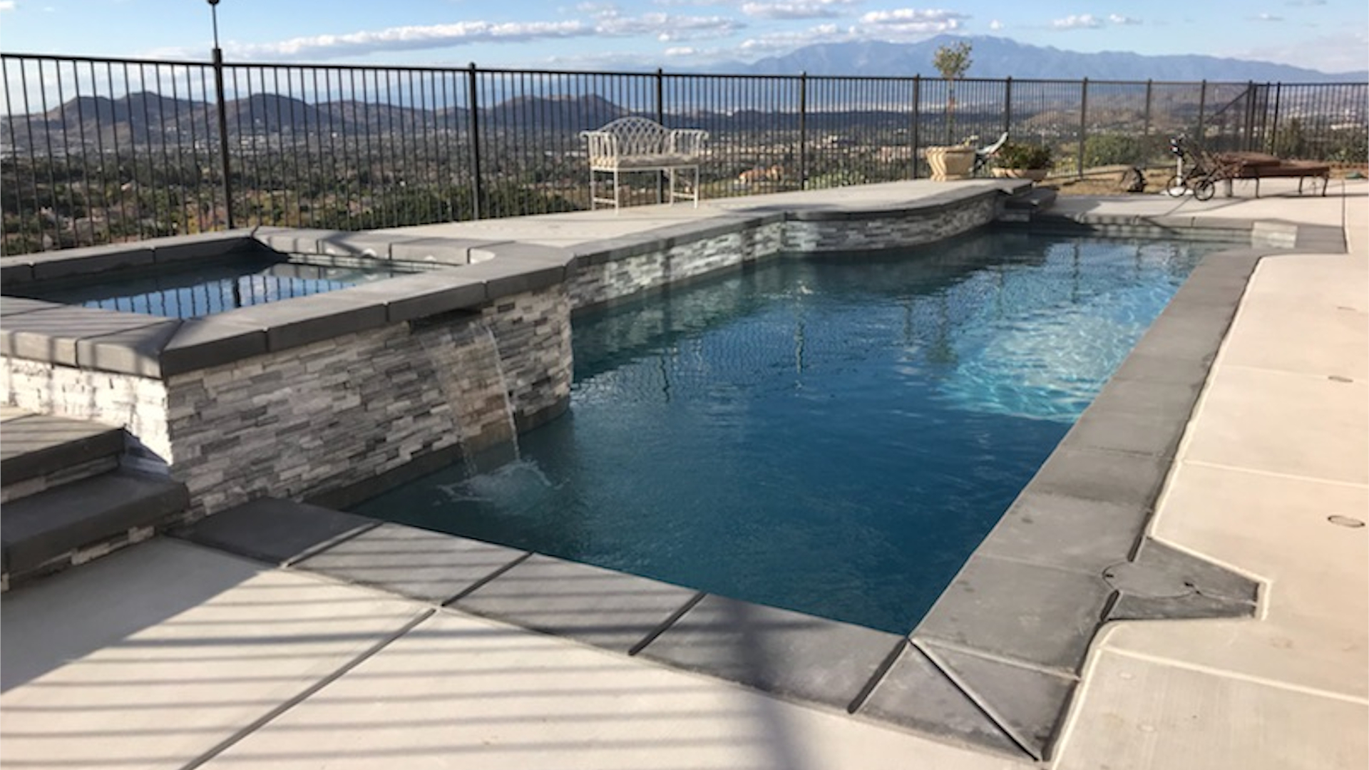 Luxury hillside pool with stone waterfall feature and panoramic valley views