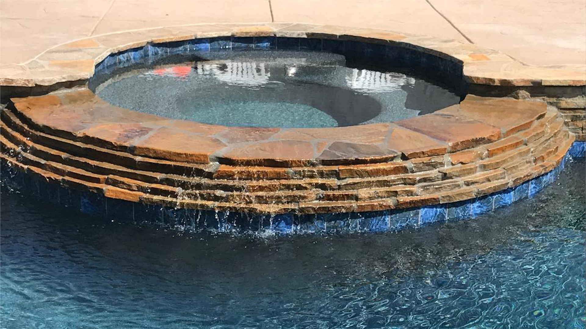 Luxury custom pool with stone coping and spa installation overlooking water